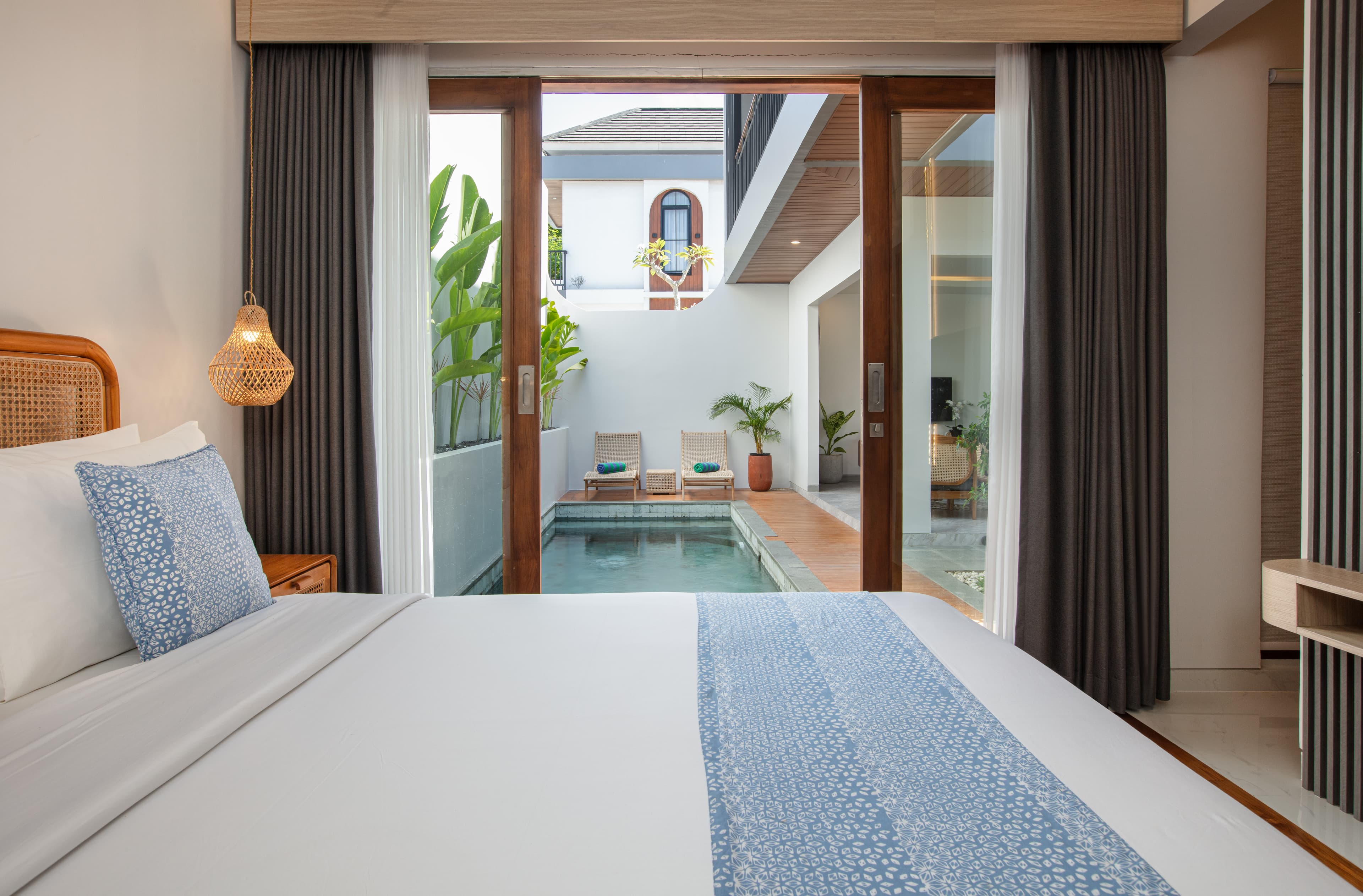 Sun-drenched bedroom with a low-profile king bed and sliding glass doors opening to a private garden courtyard